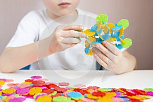A child plays with a round colored mosaic. Game process close up. Hands close up. Quarantined home art. The development of fine