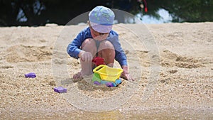 A child plays with sand and toys on the beach on a sunny hot day