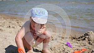 A child plays with sand and toys on the beach on a sunny hot day