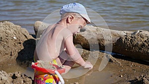 A child plays with sand and toys on the beach on a sunny hot day. Entertainment and outdoor games