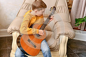 A child plays a six-string guitar at home