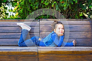 A child plays a tablet and smiles in a cafe outdoors. Childhood