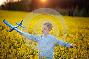 Child plays with a toy airplane in the sunset and dreams of journey in summer day