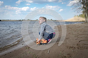 Child plays with toy car truck on the beach