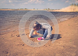 Child plays with toy car truck on the beach