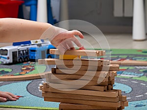 a child plays a wooden railway sitting on the floor. educational games for children. children`s hands close up.