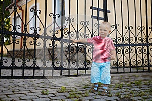 A child plays by a wrought iron grate