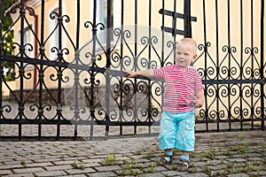 A child plays by a wrought iron grate