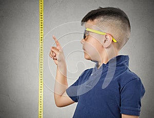 Child pointing at his height on measuring tape