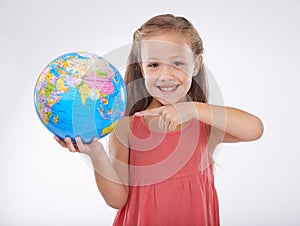 Child, pointing to globe in studio with world, planets and city for education, geography and portrait. Student, girl kid