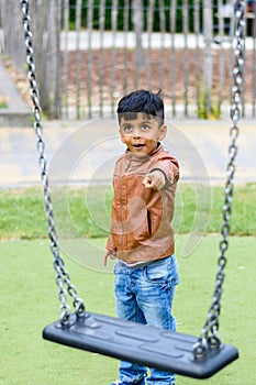 A child pointing to swing in the park; casual portrait