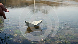 Child at the pond with a paper boat