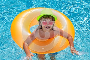 Child in pool on inflatable ring. Kid swim with orange float. Healthy outdoor sport activity for children.