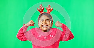 Child portrait, christmas and antlers on green screen flexing strong muscles or arms for motivation. Smile on face of a