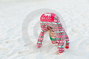 Child posing on beach wearing Christmas pyjamas