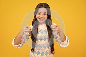 Child with positive expression, joyful and exciting over yellow background with empty space. Happy teenager girl