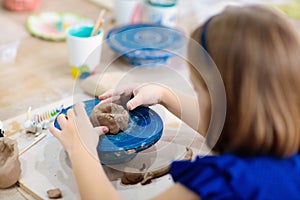 Child at pottery wheel. Kids arts and crafts class