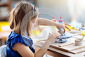 Child at pottery wheel. Kids arts and crafts class