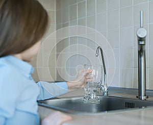 Child is pouring water from filter tap. Kitchen faucet. Quenches thirst. Filter system or osmosis, water-purification. Quality