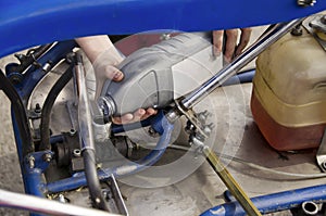 A child pours car oil into a go-kart machine