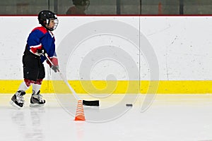 Child practices stickhandling at ice hockey practice