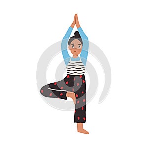 Child practicing yoga exercises and standing in tree or Vrikshasana pose. Happy smiling girl during workout. Colored