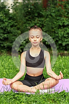 Child practicing yoga in park in day time. Girl is doing yoga in clean and green environment outdoor