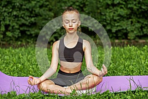 Child practicing yoga in park in day time. Girl is doing yoga in clean and green environment outdoor