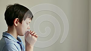 child pray. prayer believe concept. little boy folding his hands at home praying for faith in god. American a kid pray