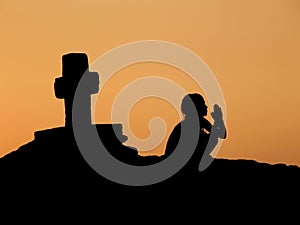 Child, prayer, cross in sunset