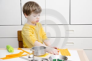 The child prepares toy food in the toy kitchen.