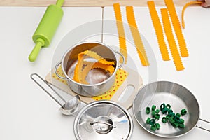 The child prepares toy food in the toy kitchen.