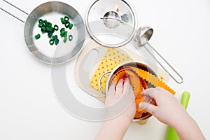 The child prepares toy food in the toy kitchen.