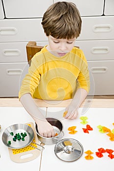 The child prepares toy food in the toy kitchen.