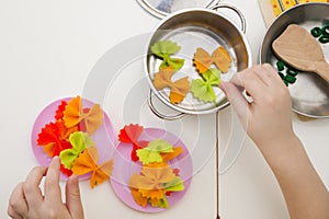 The child prepares toy food in the toy kitchen.