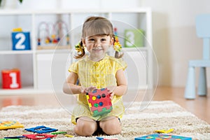 Child preschooler girl plays logical toy learning shapes and colors at home or nursery