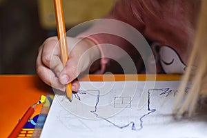 Child preschooler learns to draw and write in notebooks at home in the evening under the light from a desk lamp.