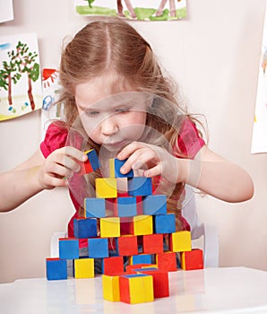 Child preschooler play wood block in play room.