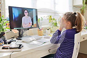 Child preteen girl studying at home using video lesson on computer