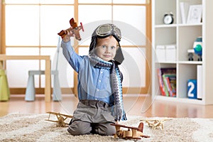 Child pretending to be aviator. Kid playing with toy airplanes at home