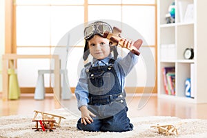 Child pretending to be aviator. Kid playing with toy airplanes at home