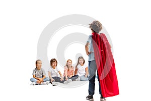 Child pretending to be a superhero with his friends sitting around