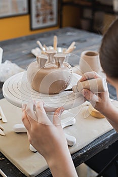 Child in the process of decorating the clay vase. Children pottery studio.