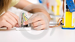 Child programming robot, working with wires, closeup