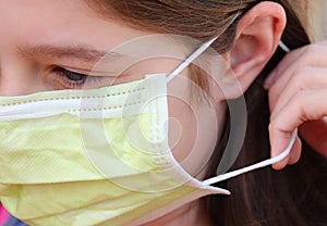 Child properly wearing surgical mask with elastic behind the ear