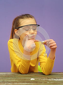 Child with protective eyeglasses makes science experiment at home with a dry fuel and calcium
