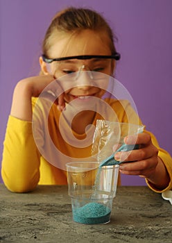 Child with protective eyeglasses makes science experiment at home with water and crystals