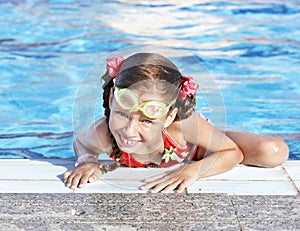 Child with protective goggles in swimming pool.