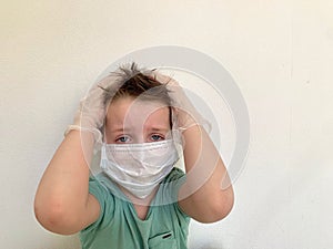 A child in a protective mask and latex gloves clutched his head, fear.