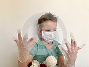A child in a protective mask looks at his hands in latex, protective gloves.